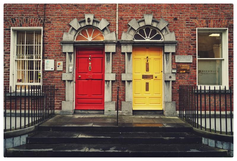 House with a red door next to a house with a yellow door 